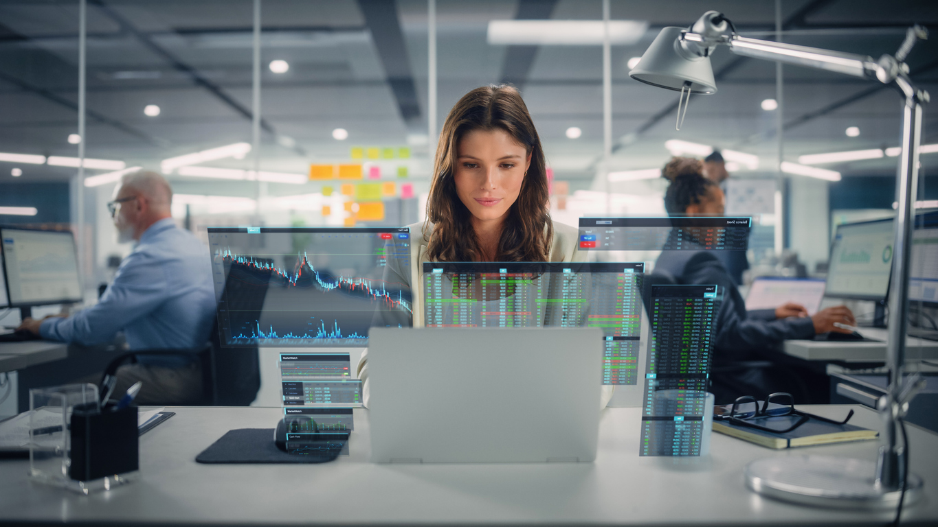 Young Happy Businesswoman Using Laptop Computer In Modern Office With Colleagues. Stylish Beautiful Financial Advisor Working. Vfx Hologram Edit Visualizing Stock Exchange Interface, Opened Charts. Young Happy Businesswoman Using Laptop Computer In Modern Office With Colleagues. Stylish Beautiful Financial Advisor Working. Vfx Hologram Edit Visualizing Stock Exchange Interface, Opened Charts.